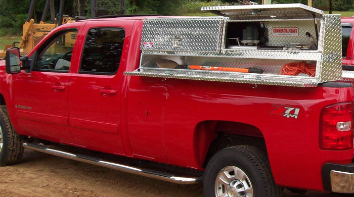 Red pickup truck with a Brute Truck toolbox on a dirt road. Large box with doors open.