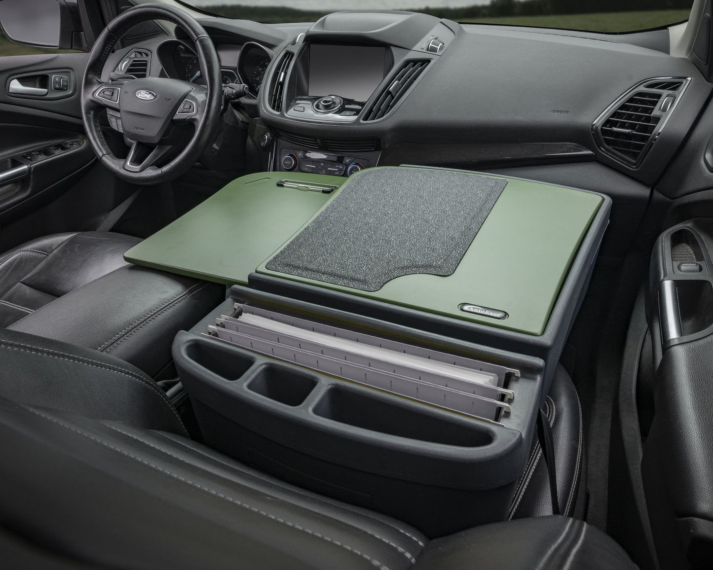 Car console with a green tray and gray mat inside a vehicle