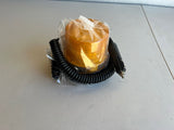 Amber warning light with black coiled cable on a white surface