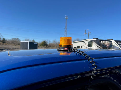 Amber warning light on a blue vehicle with a clear blue sky in the background